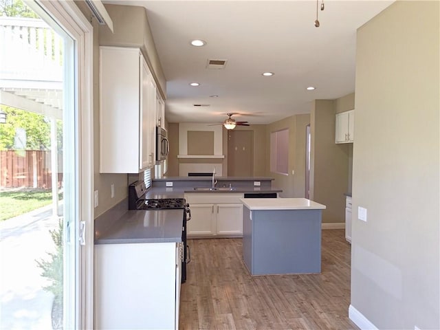 kitchen featuring a ceiling fan, a sink, white cabinetry, visible vents, and range with gas stovetop