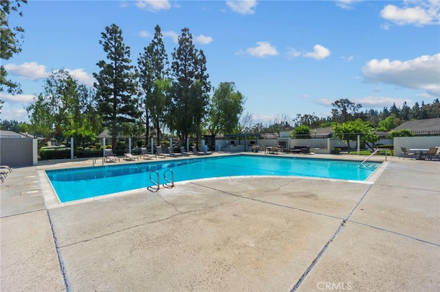 community pool with fence and a patio