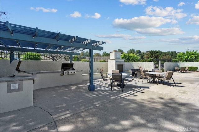 view of patio / terrace featuring fence, area for grilling, a pergola, exterior fireplace, and an outdoor kitchen