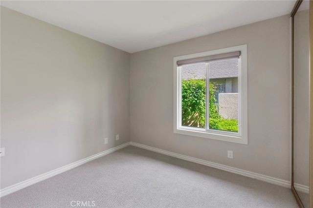 carpeted spare room featuring baseboards