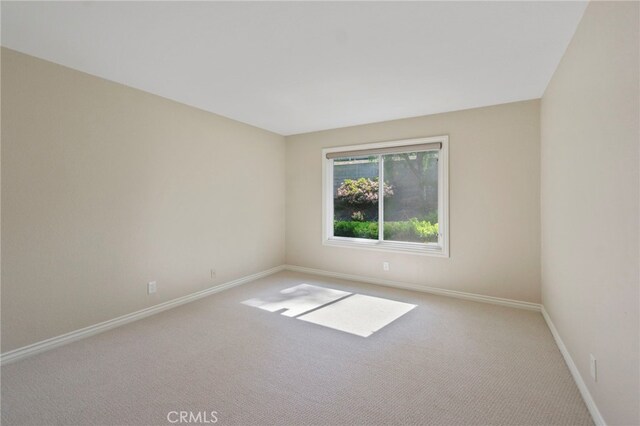 carpeted spare room featuring baseboards
