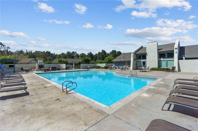 community pool with a patio area and fence