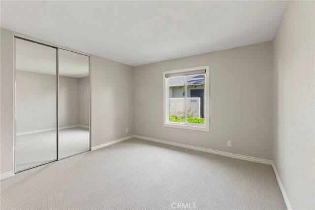 unfurnished bedroom with carpet flooring, baseboards, and a closet