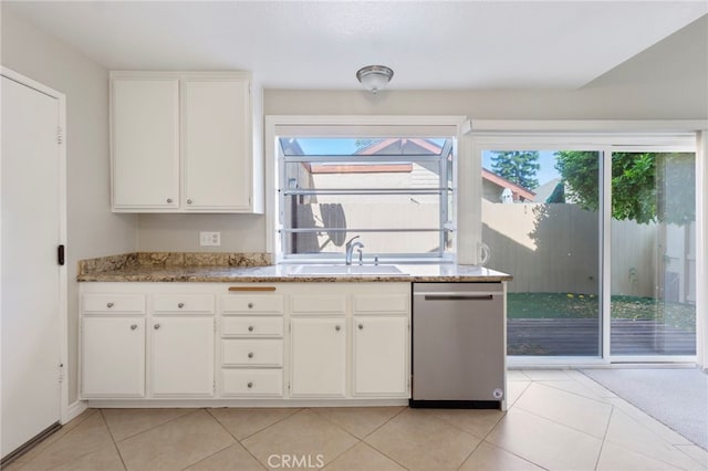 kitchen featuring a sink, stainless steel dishwasher, light tile patterned flooring, and white cabinetry