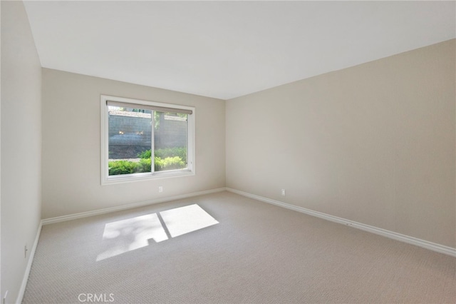empty room featuring light carpet and baseboards