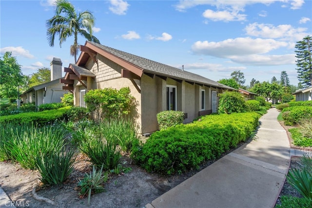 view of property exterior with a shingled roof and stucco siding