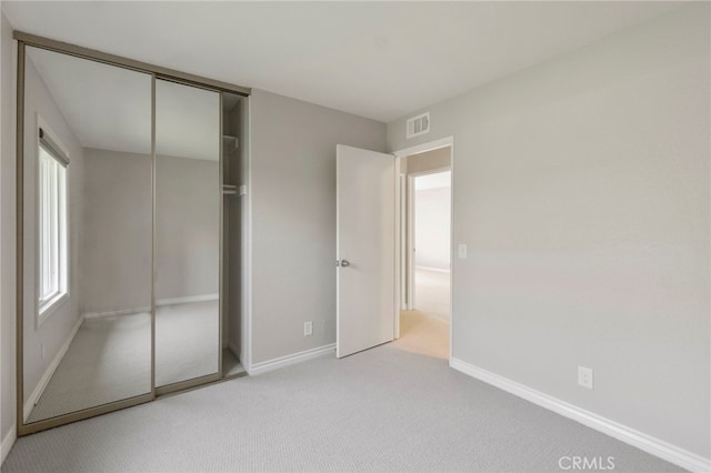 unfurnished bedroom with baseboards, carpet flooring, a closet, and visible vents