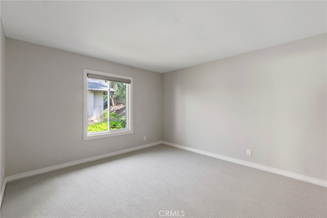 spare room featuring carpet and baseboards
