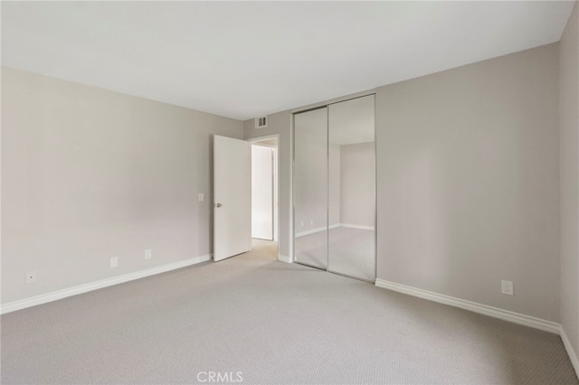 unfurnished bedroom featuring light carpet, a closet, and baseboards