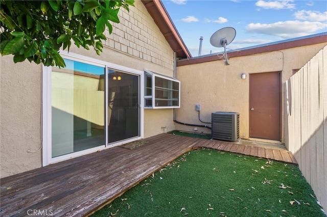 back of house with a yard, stucco siding, central AC unit, and a wooden deck