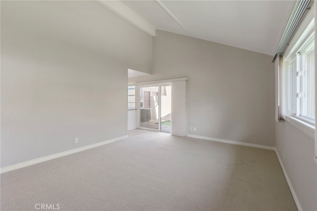 unfurnished room featuring a wealth of natural light, light carpet, baseboards, and beamed ceiling