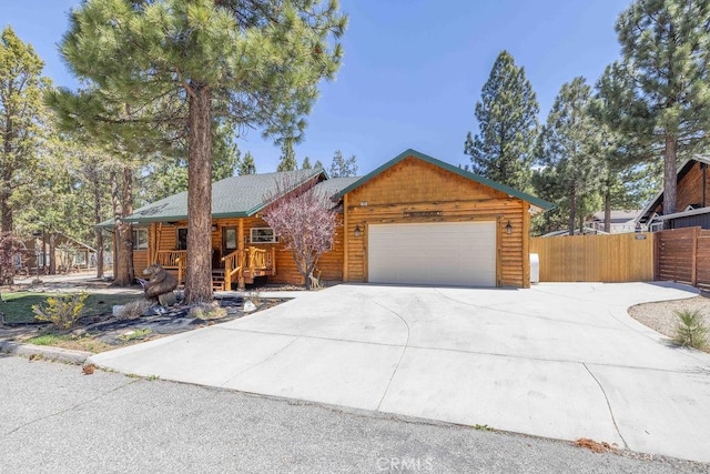 view of front of house with covered porch, driveway, an attached garage, and fence