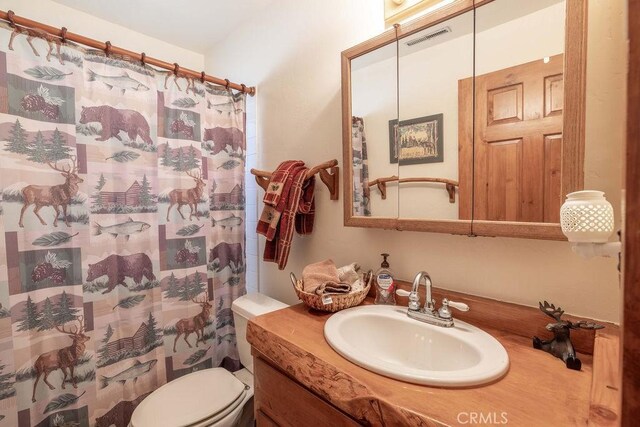 bathroom with vanity, toilet, a shower with shower curtain, and visible vents