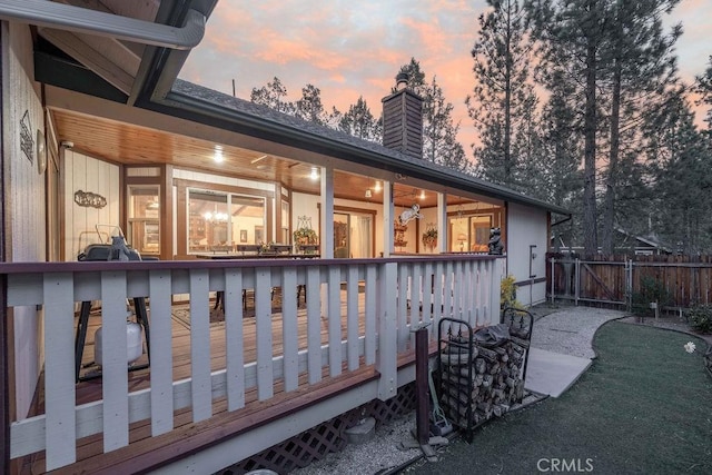 exterior space with fence, a wooden deck, and a chimney