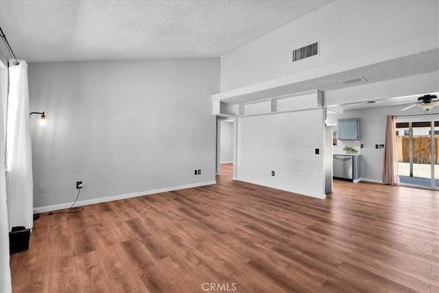 unfurnished living room featuring a ceiling fan, visible vents, a textured ceiling, and wood finished floors