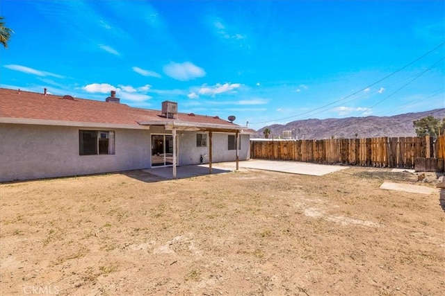 back of house featuring a patio area, a mountain view, stucco siding, and fence
