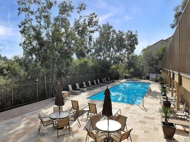 community pool with a patio and fence