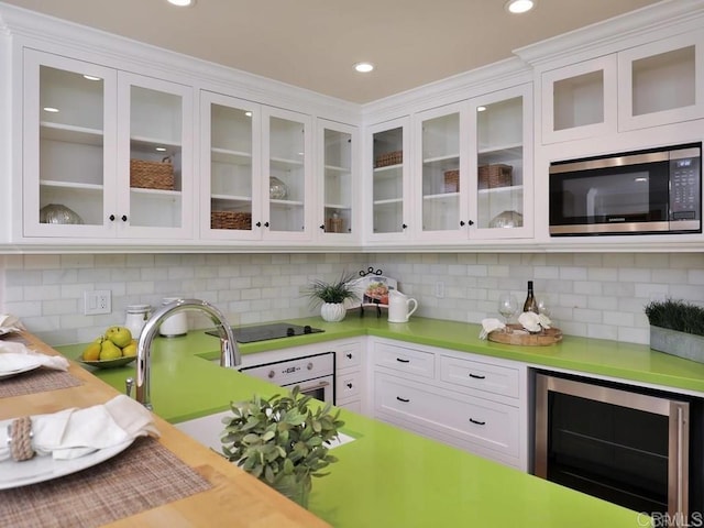 interior space featuring stainless steel microwave, wine cooler, light countertops, and white cabinets