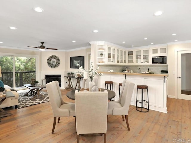 dining space featuring ceiling fan, ornamental molding, a fireplace, and recessed lighting