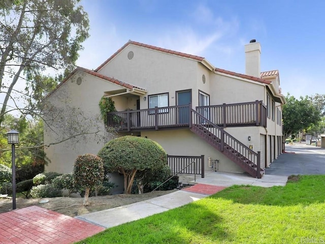 exterior space featuring a yard, stairs, stucco siding, and a chimney