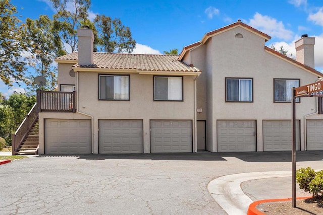 3527 Caminito Sierra Unit 202, Carlsbad, CA 92009 - rear view of house with a chimney, a tiled roof, stucco siding, and an attached garage