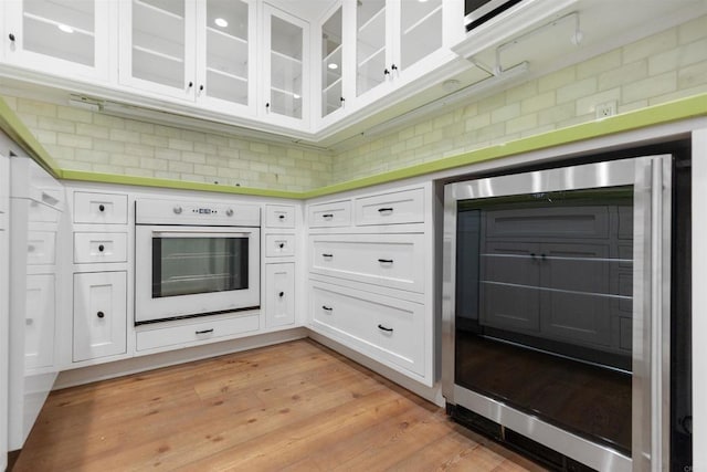 3527 Caminito Sierra Unit 202, Carlsbad, CA 92009 - kitchen featuring white oven, white cabinets, wine cooler, and glass insert cabinets