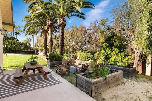 view of home's community with a yard, a garden, and a patio