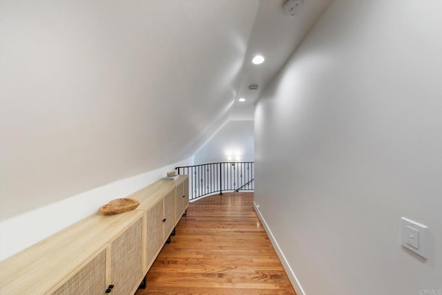 hall featuring lofted ceiling, light wood-style flooring, recessed lighting, baseboards, and an upstairs landing