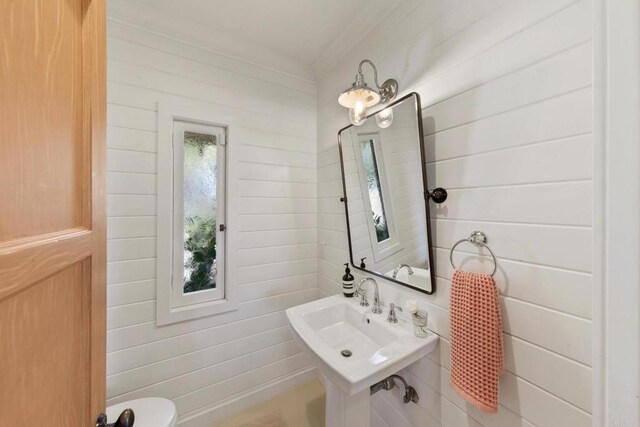 half bath with wooden walls and a sink