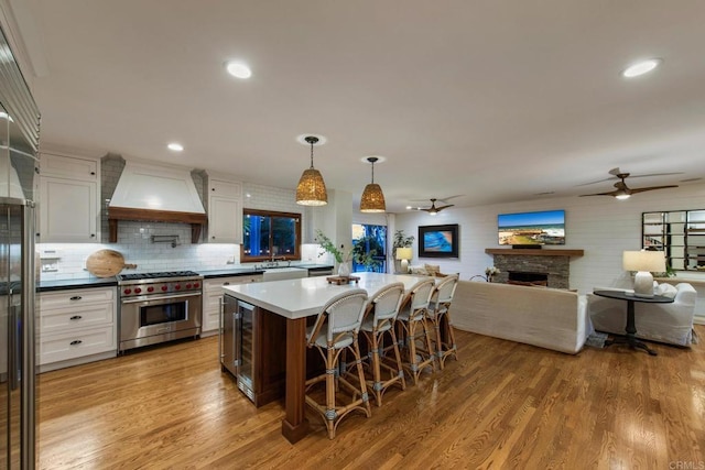 kitchen featuring premium range, light wood-style flooring, a ceiling fan, and custom range hood