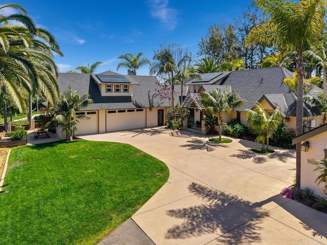 view of front of property with stucco siding, concrete driveway, solar panels, and a front yard