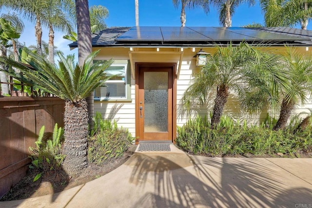 property entrance with fence and roof mounted solar panels