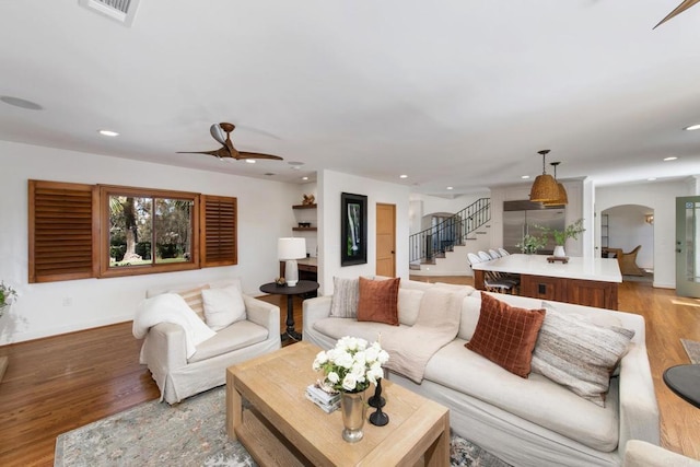living room featuring stairs, wood finished floors, recessed lighting, arched walkways, and a ceiling fan
