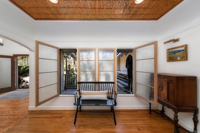 sitting room featuring wood finished floors, baseboards, arched walkways, and an ornate ceiling