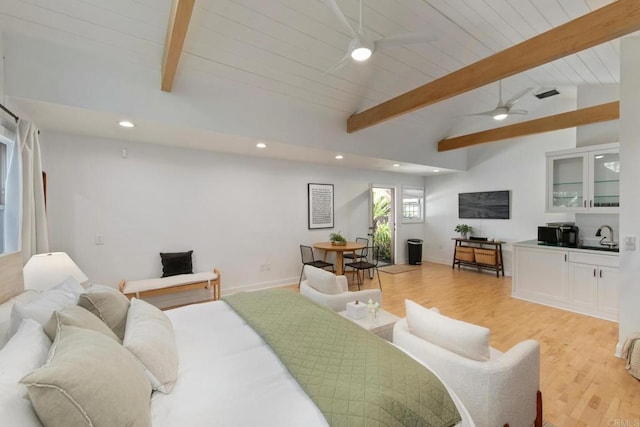bedroom with a sink, light wood finished floors, recessed lighting, and vaulted ceiling with beams