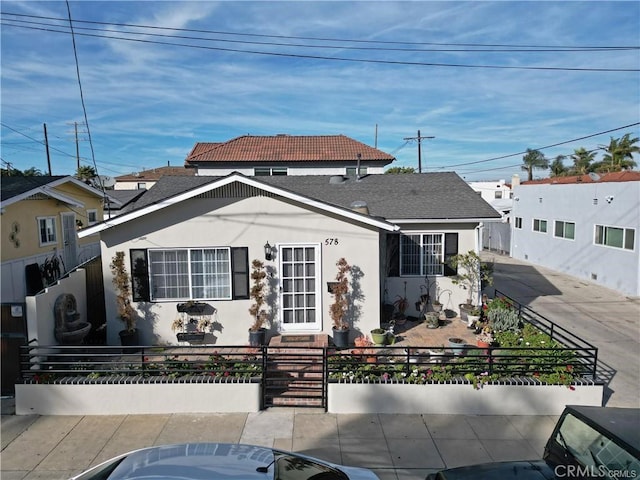 view of front of house featuring entry steps, stucco siding, and a fenced front yard