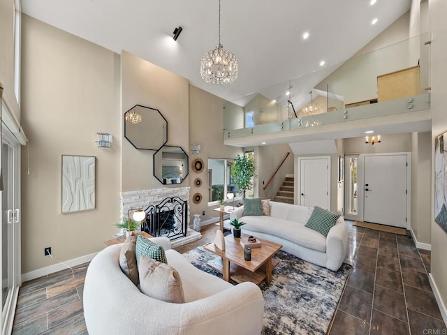 living room with a notable chandelier, a fireplace with raised hearth, baseboards, high vaulted ceiling, and stairway