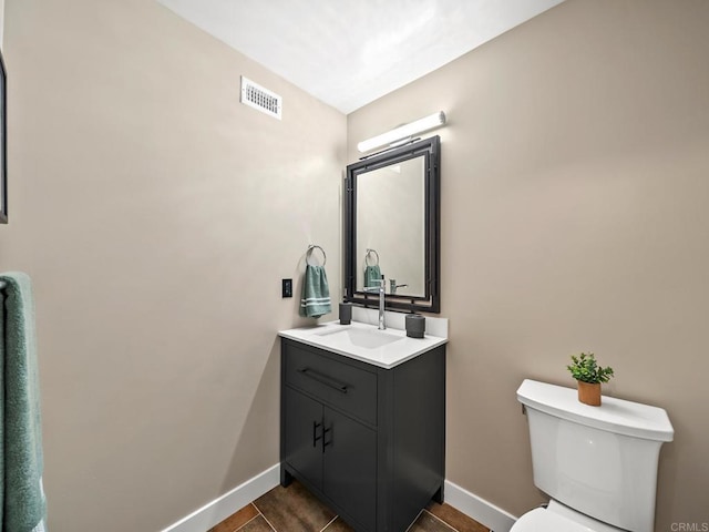 bathroom with toilet, vanity, visible vents, tile patterned floors, and baseboards