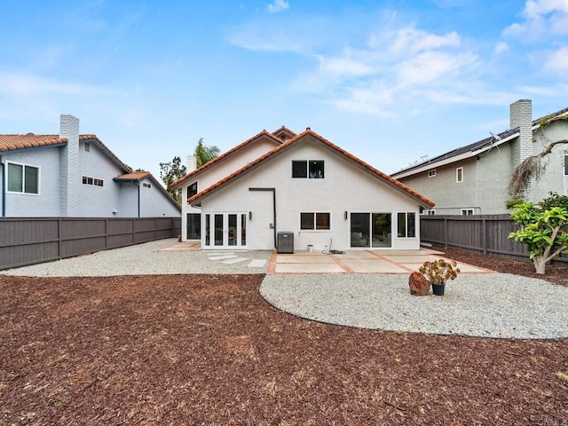 rear view of house featuring french doors, central air condition unit, a patio area, stucco siding, and a fenced backyard
