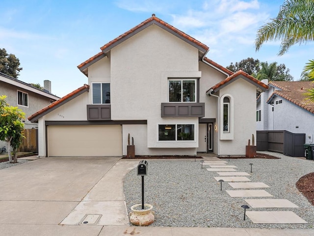 view of front facade with fence, concrete driveway, a garage, stucco siding, and a tiled roof