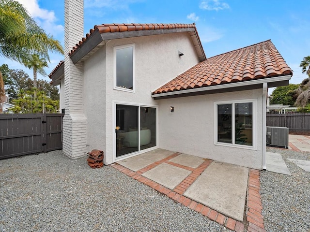 back of house with stucco siding, a tile roof, fence, central AC unit, and a patio area