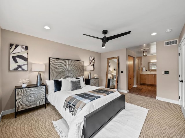carpeted bedroom featuring ensuite bath, baseboards, visible vents, and recessed lighting