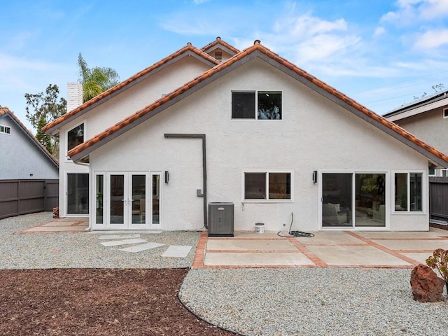 rear view of house with central air condition unit, fence, french doors, a patio, and stucco siding