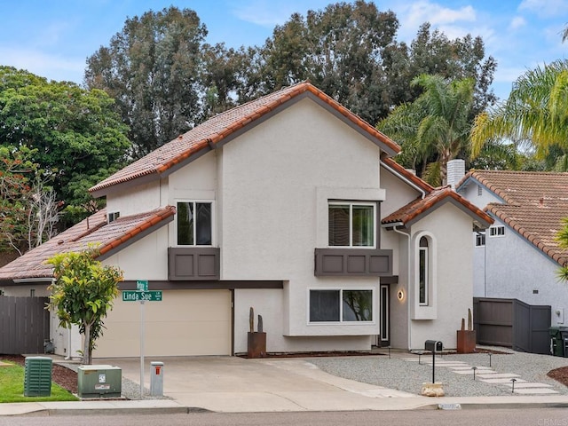 back of property featuring fence, an attached garage, stucco siding, a tile roof, and concrete driveway