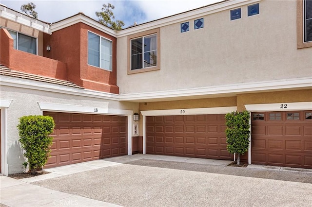 multi unit property with stucco siding and an attached garage
