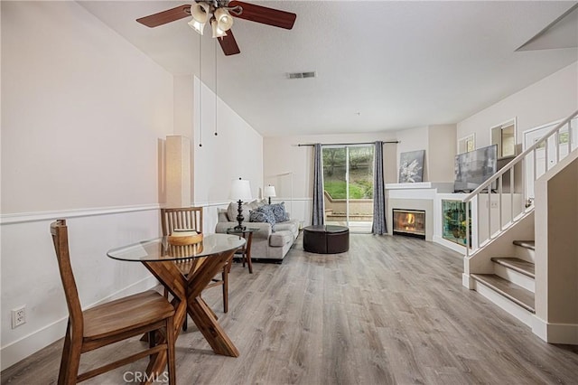 living area with a ceiling fan, stairway, wood finished floors, vaulted ceiling, and baseboards