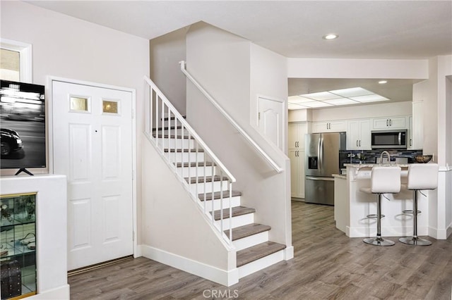 stairway featuring wood finished floors, baseboards, and recessed lighting