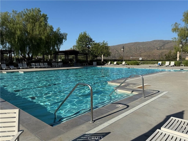 community pool with a mountain view, a gazebo, fence, and a patio