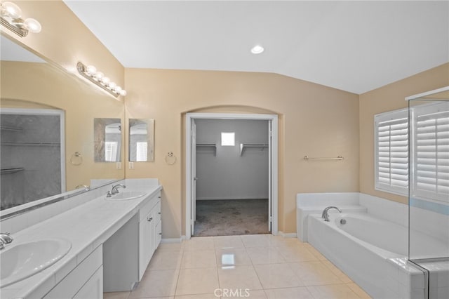 bathroom with tile patterned floors, baseboards, a bath, double vanity, and vaulted ceiling