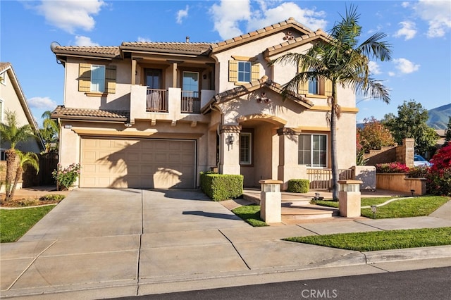 mediterranean / spanish-style home featuring a garage, a balcony, stucco siding, driveway, and a tile roof